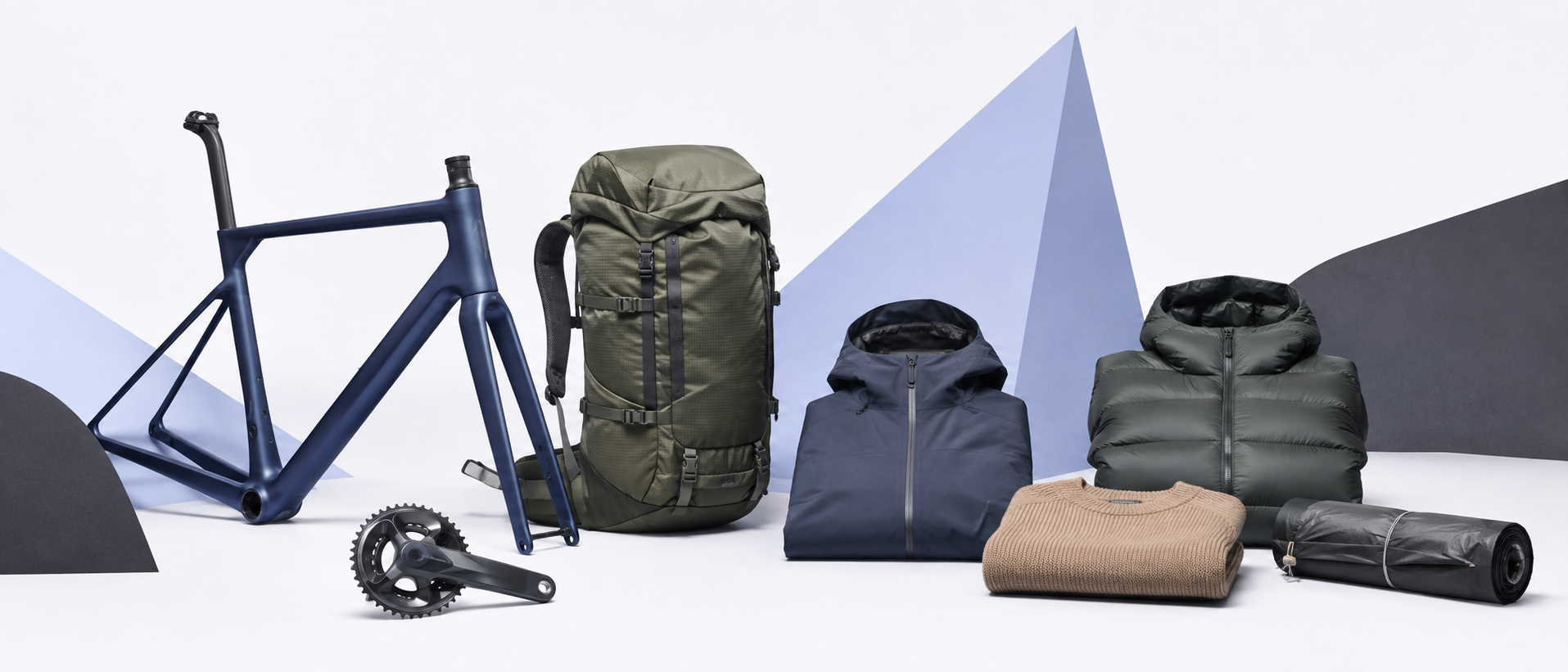 Road cycling components, a backpack, and outdoor layers arranged in a white and periwinkle studio